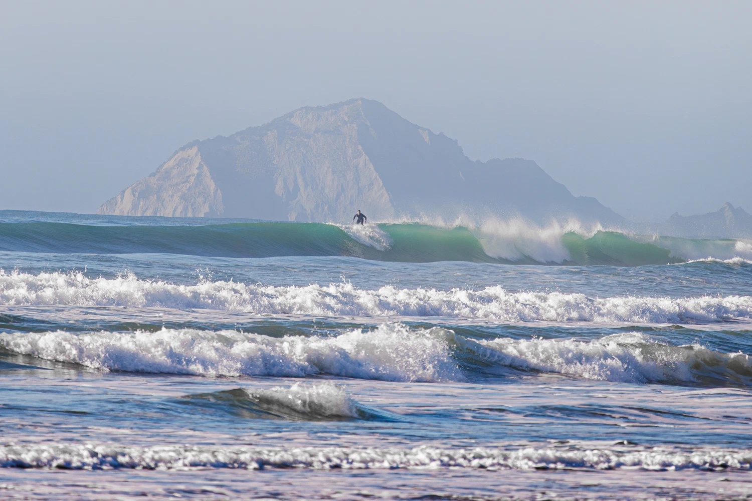 Surfers off Ocean Beach with Bare Island behind it
